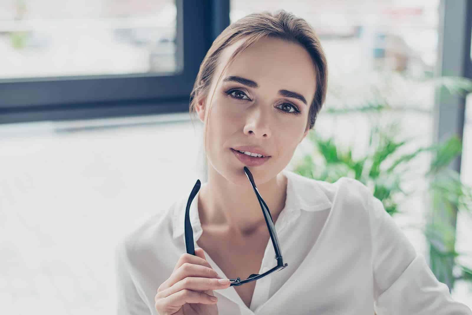 Junge Frau hält Brille in der Hand