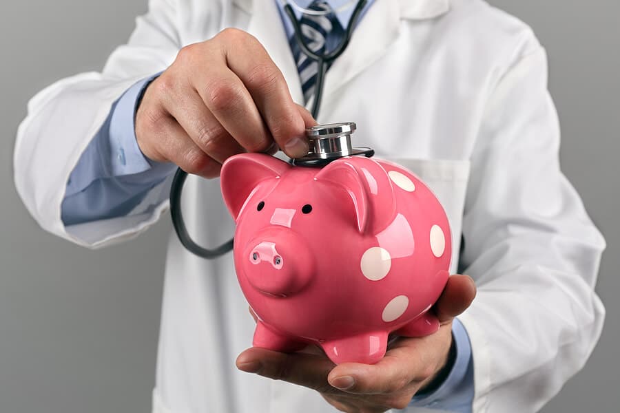Arzt horcht ein pinkes Sparschwein ab