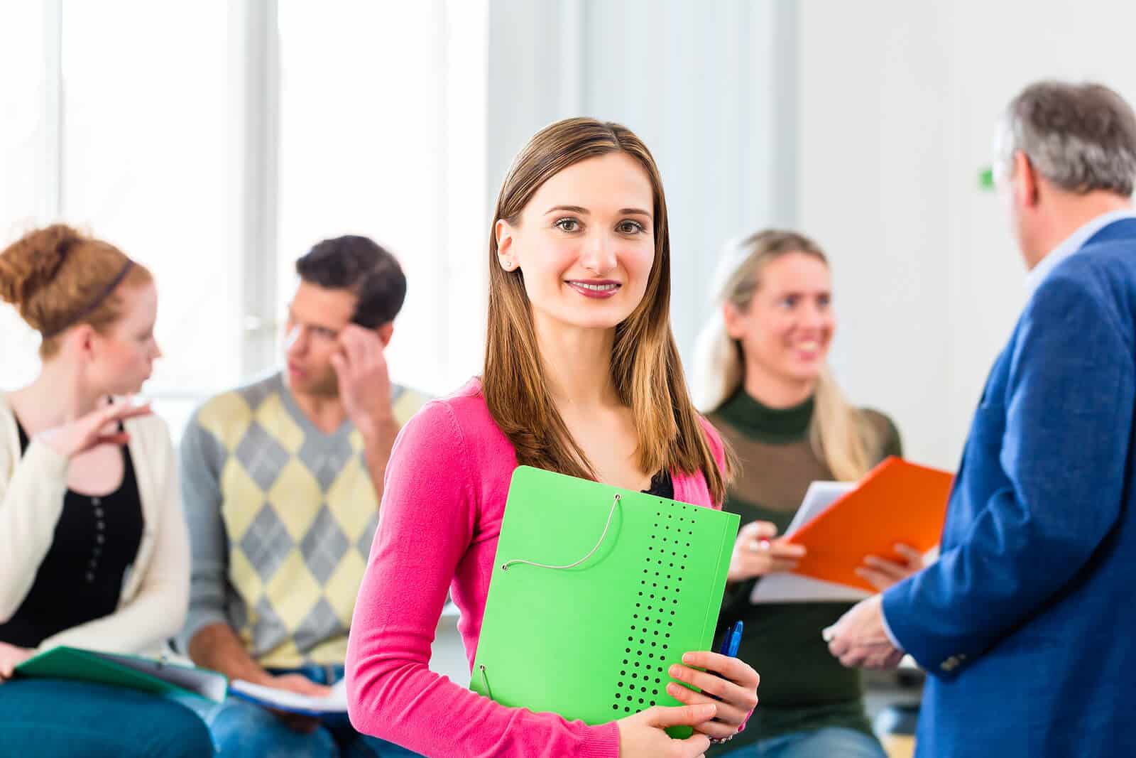 Studentin steht neben Professor und vor anderen Studenten