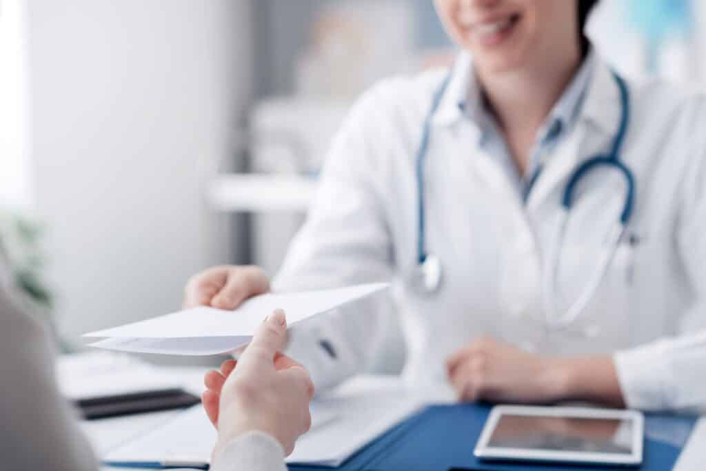 Welche private Krankenversicherung für Lehrer – Ärztin übergibt Patient ein Dokument